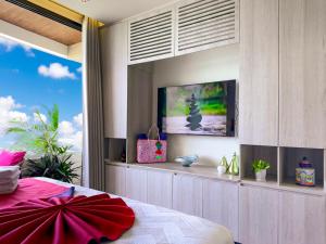 a bedroom with a bed and a tv on a wall at Casa La Aurora - Beachfront Studio and Rooftop Infinity Pool in Puerto Morelos