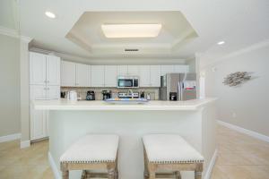 a kitchen with white cabinets and a counter with stools at Phoenix on the Bay 1206 in Orange Beach