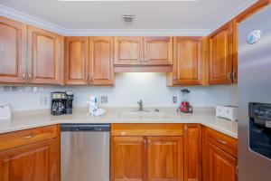 a kitchen with wooden cabinets and a sink at Phoenix on the Bay 1528 in Orange Beach +47 photos