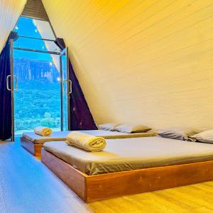 two beds in a room with a large window at A frame Riverston in Matale
