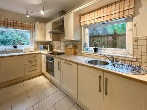 a kitchen with white cabinets and a sink at Garden View Cottage - Uk50886 in Cupar