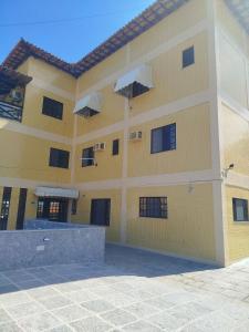 a large yellow building with windows on it at Condomínio Pousada Amarela 100 metros da Praia in Iguaba Grande