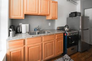 a kitchen with wooden cabinets and a sink and a refrigerator at Hoboken Studio 15 Min from Manhattan in Hoboken