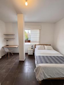 a bedroom with a bed and a desk and a window at La Arteza Pacasmayo in Pacasmayo