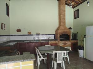 a kitchen with a table and a brick oven at Condomínio Pousada Amarela 100 metros da Praia in Iguaba Grande