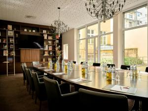 a long table with chairs in a room with windows at Flemings Hotel Wien-Stadthalle in Vienna