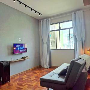 a living room with a couch and a television at Centro de BH, Ar-Condicionado, Wi-Fi Rápido, 6min Rodoviária, Portaria 24h in Belo Horizonte