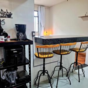 a kitchen with a counter and three bar stools at Centro de BH, Ar-Condicionado, Wi-Fi Rápido, 6min Rodoviária, Portaria 24h in Belo Horizonte