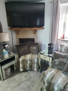 a living room with a flat screen tv above a fireplace at Lamb Cottage Bed and Breakfast in Box