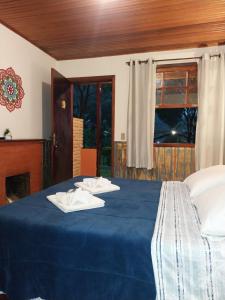 a bedroom with a blue bed with towels on it at Chalé Refúgio na Alameda Maringá MG in Bocaina de Minas