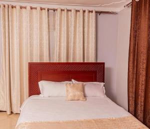 a bed with a red headboard in a bedroom at Alma Hotels Kampala in Kampala