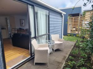 a patio with wicker chairs and a glass table at Sailrock Studio in Mangawhai