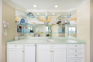 a kitchen with a sink and glass shelves at Phoenix on the Bay 1303 condo in Orange Beach