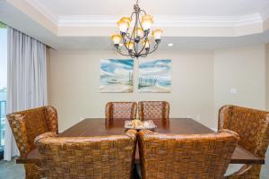 a dining room table with wicker chairs and a chandelier at Phoenix on the Bay 1303 condo in Orange Beach