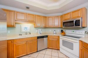 a kitchen with wooden cabinets and white appliances at Phoenix on the Bay 1405 in Orange Beach