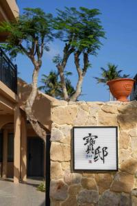 a sign on a stone wall with trees in the background at Bao Di East Coast in Honghai