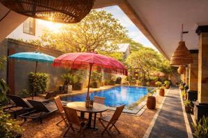 a patio with a table and umbrella next to a swimming pool at Tendan Residence in Legian