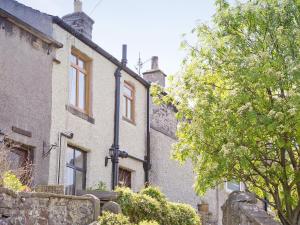 an old stone house with a tree in front of it at Millstone Cottage in Bradwell