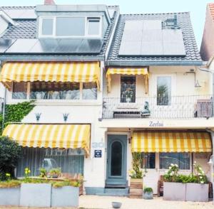 a white house with yellow striped awnings on it at Boutique hotel Zeelui in Egmond aan Zee