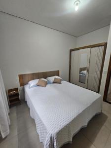 a bedroom with a large bed with white sheets at Apartamento completo - a 3 minutos do centro in Alta Floresta