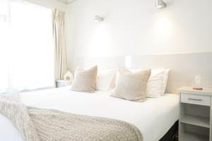 a bedroom with a white bed with white pillows at Bay Motel in Byron Bay
