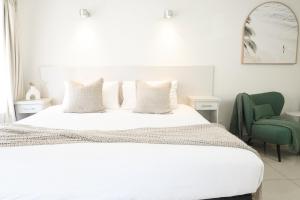 a bedroom with a white bed and a green chair at Bay Motel in Byron Bay