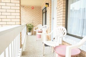 a row of white chairs sitting on a balcony at Bay Motel in Byron Bay +11 photos