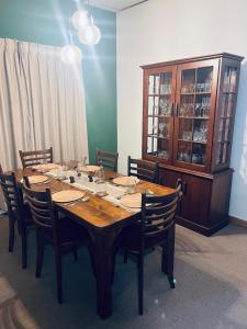 a wooden table with chairs and a china cabinet at Ceylon Airport Apartment in Raddoluwa +17 photos