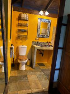 a yellow bathroom with a toilet and a sink at My Mountain Home - Le Chalet in Afaahiti
