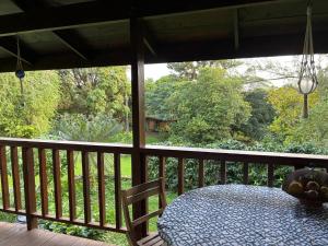 a table on a porch with a view of a forest at My Mountain Home - Le Chalet in Afaahiti