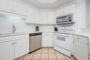 a white kitchen with white cabinets and a microwave at Phoenix on the Bay 1217 in Orange Beach +47 photos