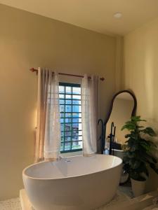 a large white tub in a bathroom with a window at Gác Homestay Phan Thiết in Ấp Sung Xuân +97 photos
