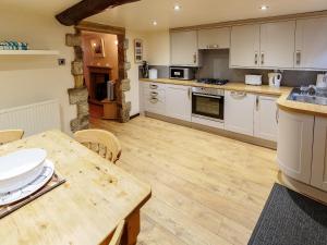 a kitchen with white cabinets and a wooden table at Millstone Cottage in Bradwell