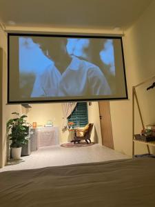 a large projection screen in a room with a table at Gác Homestay Phan Thiết in Ấp Sung Xuân