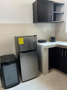 a small kitchen with a refrigerator and a trash can at Casa Papalo in Palenque