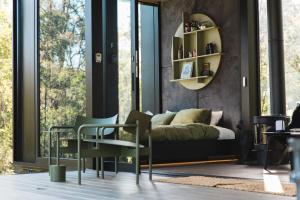 a bedroom with a bed and chairs in front of a window at The Lookout - a Huch experience in Wollombi