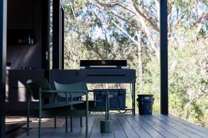 a piano and chairs on a porch with trees at The Lookout - a Huch experience in Wollombi