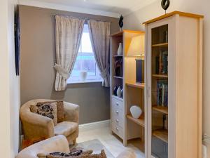 a living room with a chair and a book shelf at Four Seasons - Hw7432 in Tal-gareg