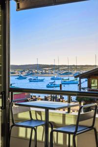 a table and chairs on a balcony with boats in the water at 456 Embarcadero Inn & Suites in Morro Bay