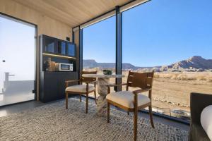 a room with a table and chairs and a view of the desert at Luxury Glass Tiny House and Sauna in Torrey