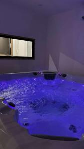 a hot tub with blue water in a room at Instant Charnel Sauna et Jacuzzi Privatif in Istres +1 photo