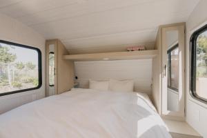 a white bed in a small room with windows at Glamping Trailer Lanikai in Awaji