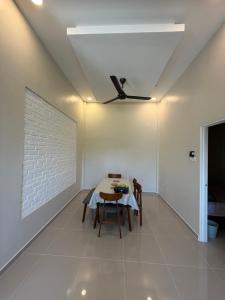 a dining room with a table and a ceiling fan at Homestay Lanai Kemboja Sungai Buloh in Shah Alam