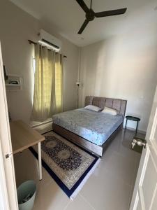 a small bedroom with a bed and a table at Homestay Lanai Kemboja Sungai Buloh in Shah Alam