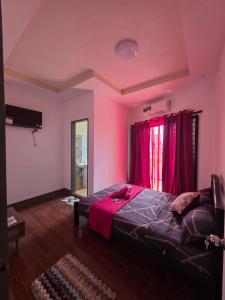 a pink bedroom with a bed and a window at Rweydz Guest Inn in Tagbilaran City