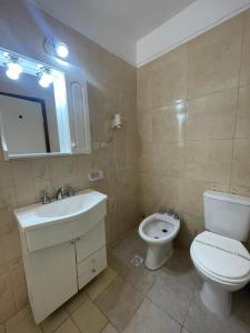 a bathroom with a white toilet and a sink at Hotel Pleno Sol in Villa Gesell