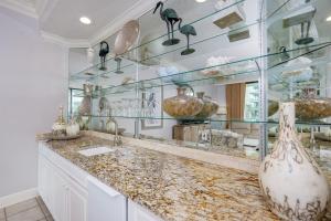 a kitchen with a counter with glass shelves at Phoenix on the Bay 1129 condo in Orange Beach