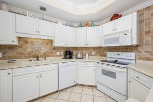a white kitchen with white cabinets and appliances at Phoenix on the Bay 1415 in Orange Beach