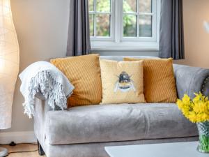 a grey couch with pillows on it in a living room at Wisteria Cottage in Heathfield