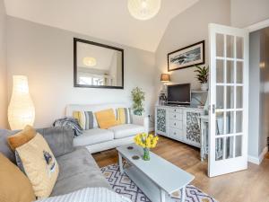 a living room with a couch and a tv at Wisteria Cottage in Heathfield